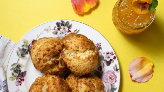 Biscuits on a plate with flowers and a cocktail in the top right.