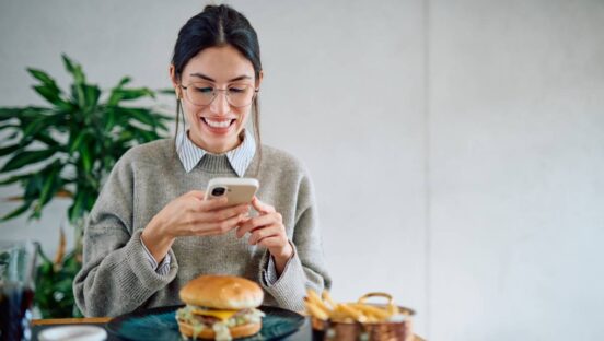 Adobe stock woman at a restaurant taking a picture of her burger.