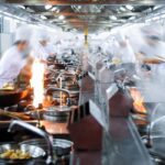 Crowded restaurant with blurred chefs.
