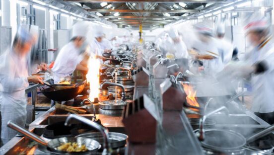 Crowded restaurant with blurred chefs.