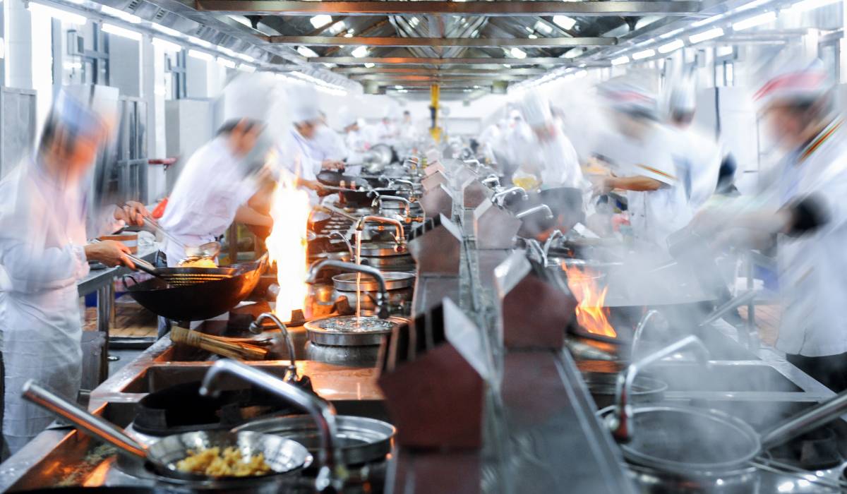 Crowded restaurant with blurred chefs.