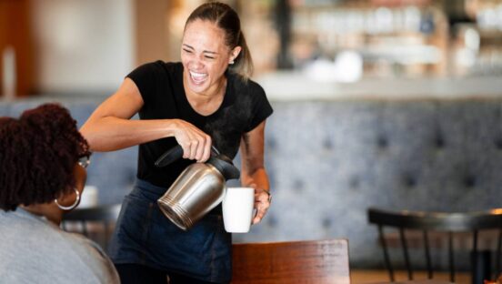 First Watch employee serving coffee to a customer.