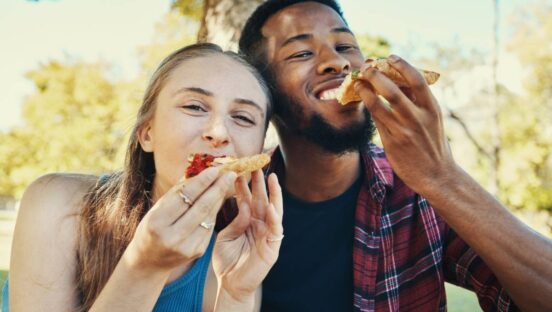 Two Gen Z people eating slices of pizza.
