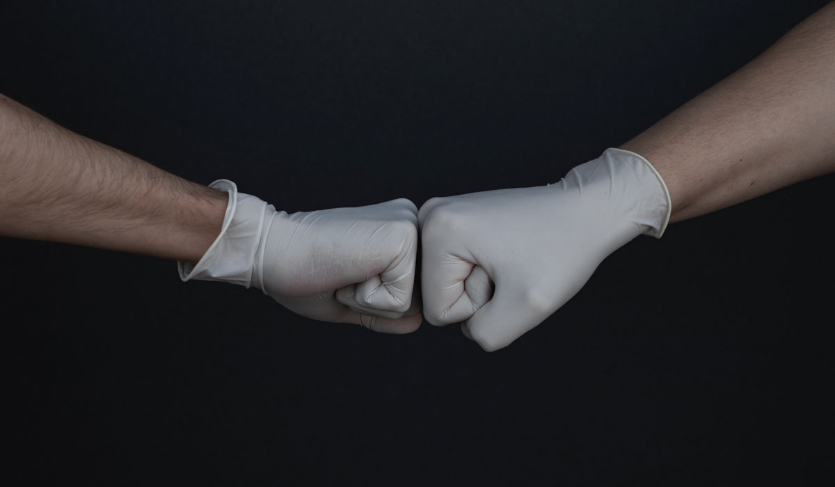 Two People Wearing Gloves Doing A Fist Bump