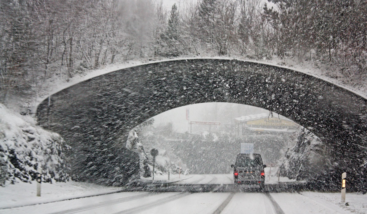 A Car Drives Under A Bridge In A Snow Storm
