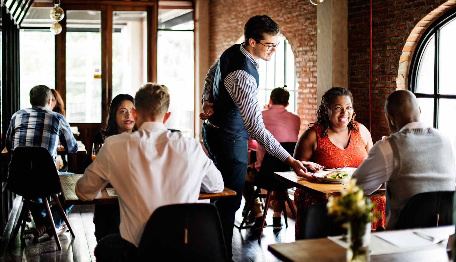 Busy Restaurant And Waiter Serving Customers
