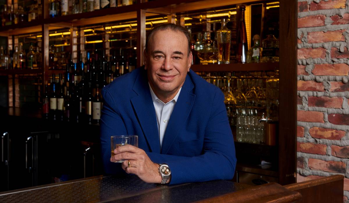 Jon Taffer holding a drink in a bar setting.