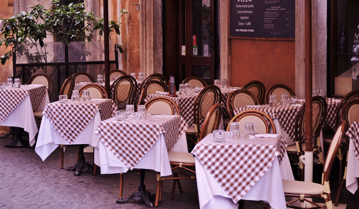 A Row Of Empty Tables Outside A Cafe