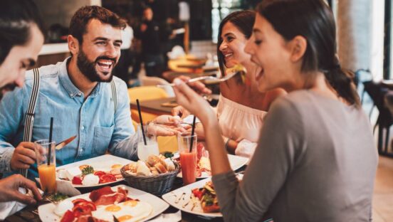 Group of happy friends having breakfast in the restaurant.