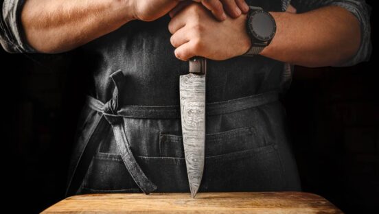 Restaurant knife on a cutting board held by a chef.