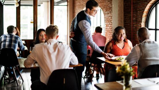 Restaurant waiter bringing food to a table.