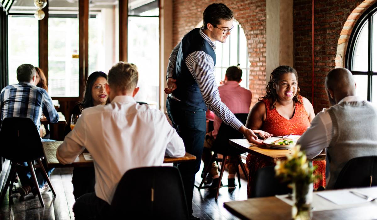 Restaurant waiter bringing food to a table.