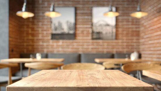 Empty coffee table over defocused coffee shop background with copy space.