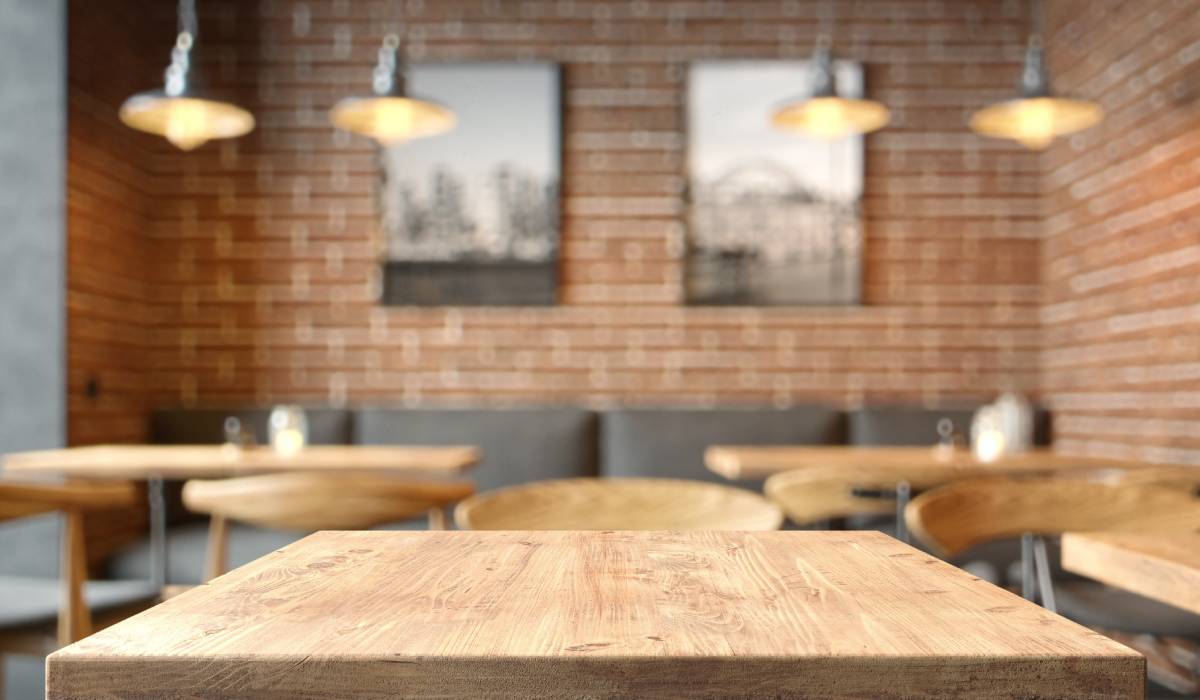 Empty coffee table over defocused coffee shop background with copy space.